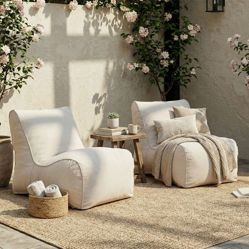 Decozie Designer Level Transformation on a Budget Two cozy cream outdoor lounge chairs placed on a natural jute rug. A simple wooden side table and climbing pink flowers complete this serene and affordable patio design.