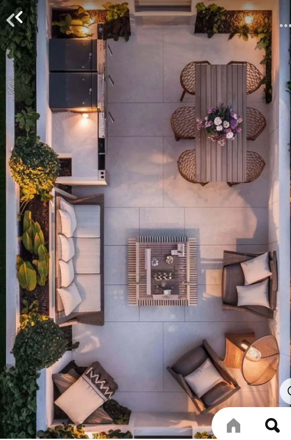 Decozie Curated Multi-Zone Outdoor Living Space Top-down aerial photograph of a masterfully curated multi-zone outdoor living space. The design, perfect for a modern patio or rooftop terrace, features a fully integrated outdoor kitchen area with a professional grill and integrated lighting at the top-left. Adjacent is a sophisticated outdoor dining area with a large wooden table, matching woven chairs, and a central floral arrangement. A modern slatted coffee table on a large tile surface divides the zones. Below, a generous corner wicker sectional sofa with plush, light-colored cushions and coordinated accent pillows, and an individual accent armchair with a distinct floor-standing lantern, create extensive lounge areas. The space is defined by low white walls, built-in planters with architectural trees, lower-level landscape lighting, and an inviting dusk atmosphere. This showcases a complete, personalized, designer-level layout plan.